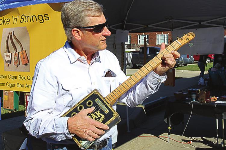 J.C. VENTIMIGLIA | Staff BRENT KASL strums one of the cigar box guitars he makes and sells.