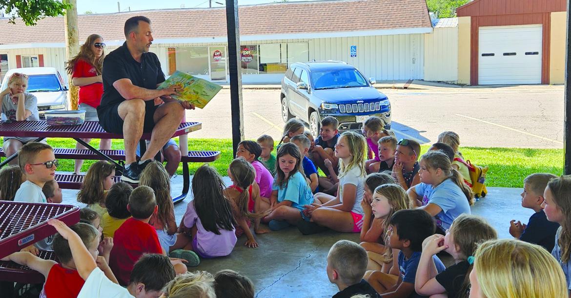 DR. NELSON KANNING of Kanning Dental reads a children’s book about good dental hygiene to youth participants during a program at Lawson City Park. After the story, kids colored dentalthemed activity pages. MIRANDA JAMISON  Staff
