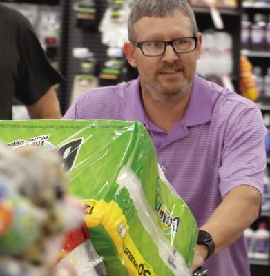JEREMY POWELL fills the shopping cart with paper goods and cleaning products. Powell of Excelsior Springs was the winner of the Grocery Grab, hosted by Excelsior Springs and Lawson Rotary clubs. See more photos on page 12.