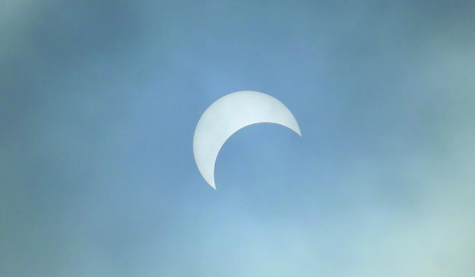 EXCELSIOR SPRINGS residents gathered at Blue Sparrow Garden Center to witness a once-in-alifetime event to see a partial solar eclipse as the clouds cleared. ELIZABETH BARNT | Staff