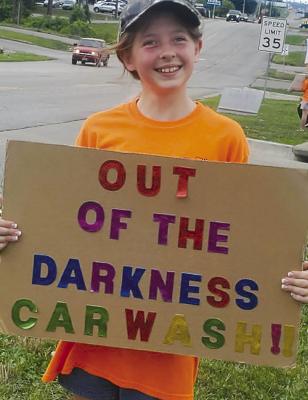 Grace Souders holds a sign to gain community interest in the car wash.