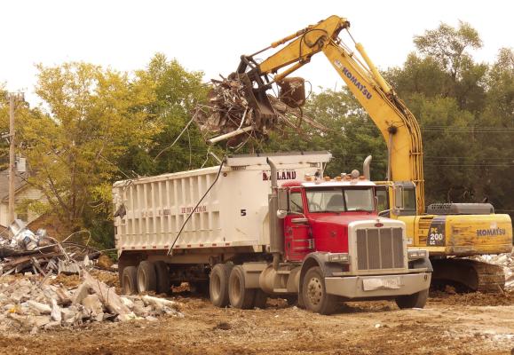 ELIZABETH BARNT | Staff Excavators lift debris into dump trucks to clear the area for the new school.