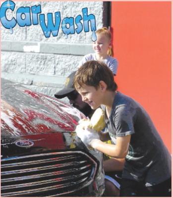 The Excelsior Springs Tigers nine and under baseball team held a car wash fundraiser at AutoZone recently to raise funds for their team. Carter Lawson suds up the car with a smile on his face to support his baseball team.