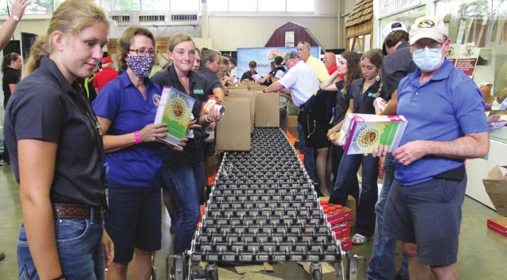AT THE MISSOURI State Fair, at the front, left and right, are Isabella Kamler and Mark Gunby. They pack boxes for Missouri families in need of food. J.C. VENTIMIGLIA | Staff