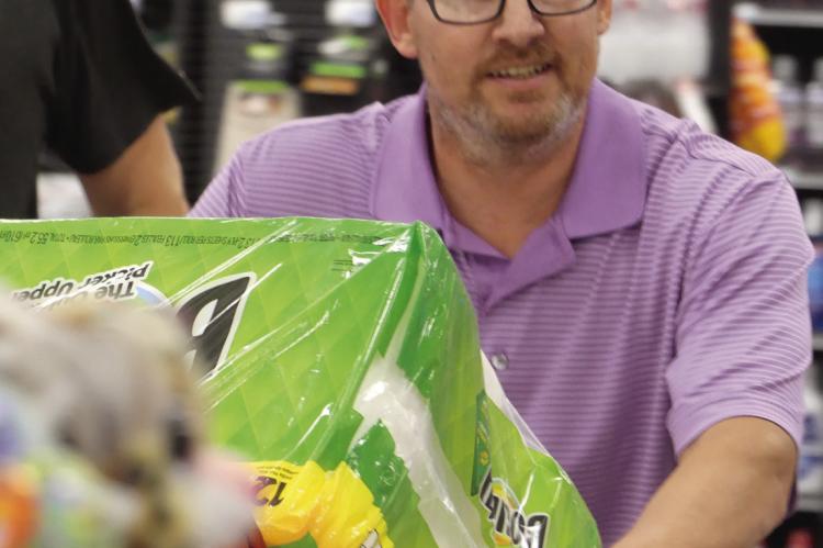 JEREMY POWELL fills the shopping cart with paper goods and cleaning products. Powell of Excelsior Springs was the winner of the Grocery Grab, hosted by Excelsior Springs and Lawson Rotary clubs. See more photos on page 12.