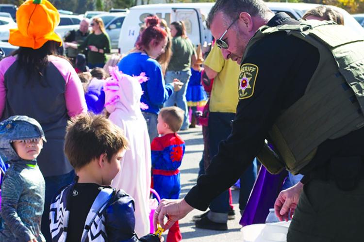 MAJ. ROBERT HAYES passes out candy at a trunk or treat event. Submitted