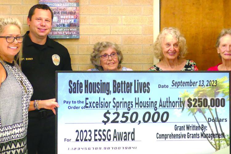 CARRIE HILTNER (from left), Police Captain Robert Warner, Barbra Blubaugh, Pat Owens and Sharon Williams holds up a check for $250,000 in grant funds for the Excelsior Springs Housing Authority. ELIZABETH BARNT | Staff