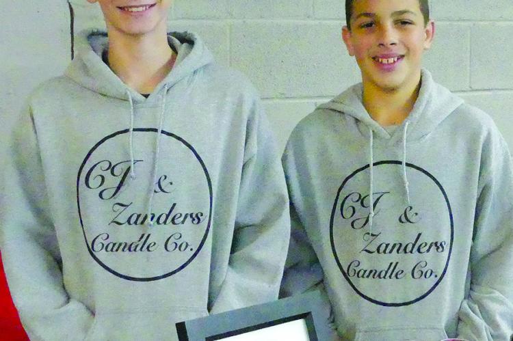 CAMDEN JOHNSON (left) and Zander Wilkins set up their booth of candles to sell to patrons at the Winter Market.