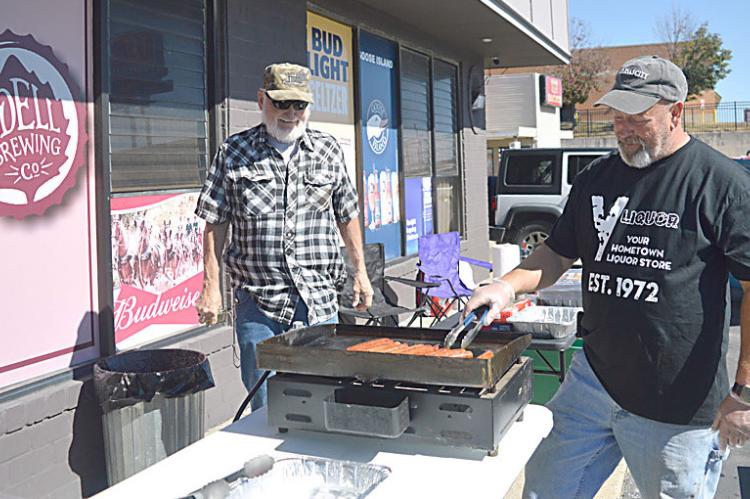 JOHN HONEYCUTT, right, grills hotdogs for visitors during Customer Appreciation Day while under the watchful eye of Lowry Ford. TARA ALTIS | The Standard
