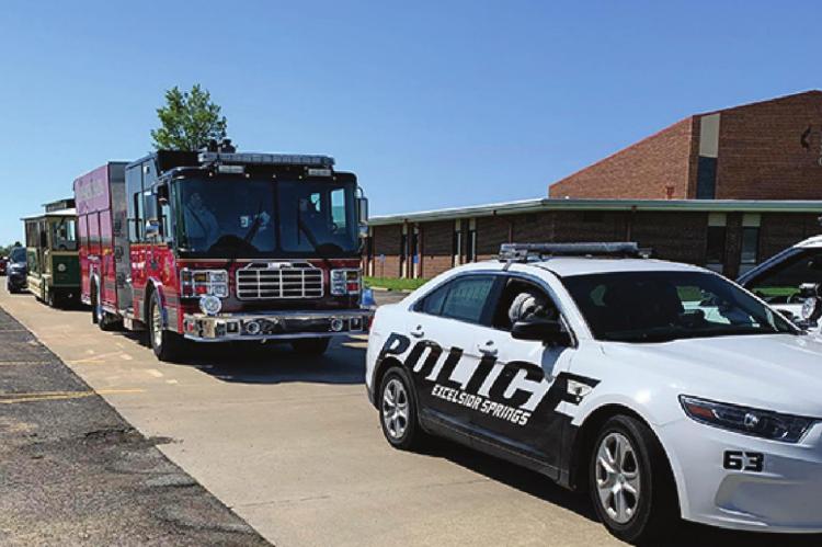 A POLICE CRUISER, a fire truck and the chamber trolley park at First United Methodist Church before the parade.