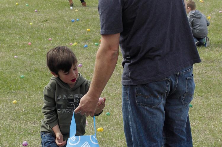 VINCENT ARCHER, 4, (left), fills his bag with Easter eggs with help from his father.