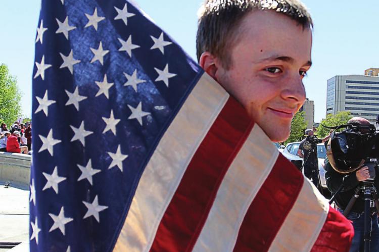 AMONG THE PROTESTERS, Justin Ford, 19, carries an American flag. J.C. VENTIMIGLIA | Staff