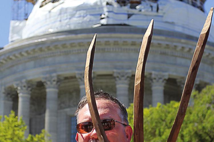 A PROTESTOR, Todd Isaac “Ike” Skelton, stands in front of the Capitol on Tuesday with a pitchfork of a sort used by American Revolutionary War-era farmers. He says he wants Gov. Mike Parson’s stay-home order lifted.
