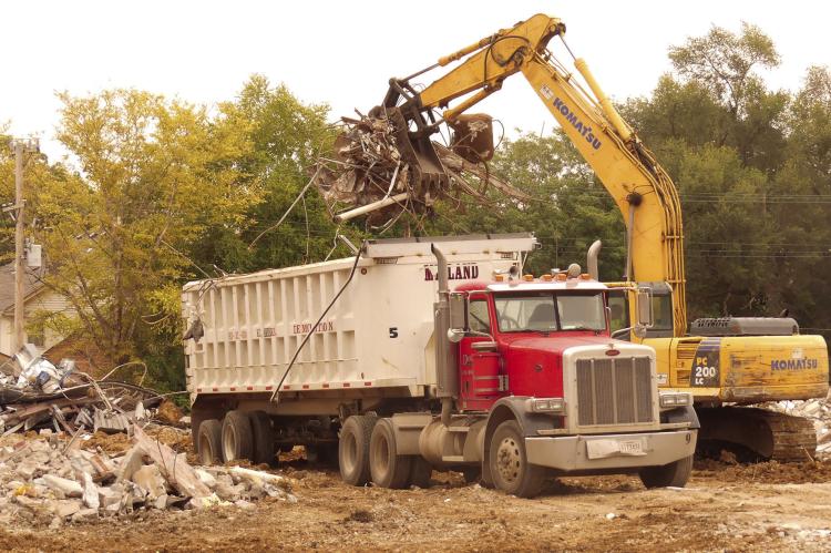 ELIZABETH BARNT | Staff Excavators lift debris into dump trucks to clear the area for the new school.