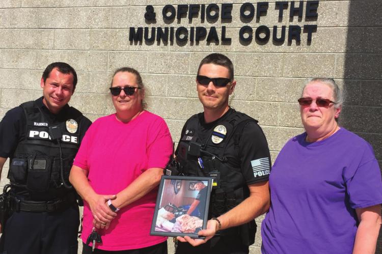 SISTERS Gail Vassmer and Julane Hicks show appreciation for the Excelsior Springs Police Department. From left are Officer Robert Warner, Vassmer, Officer Kenneth Stieh and Hicks. The sisters present Stieh with their thanks and a framed photo of Stieh and their mother, Madolyn Eberts, taken during one of Stieh’s visits with Eberts in the hospital.