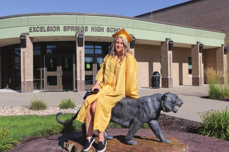 ON GRADUATION DAY, Excelsior Springs High School senior Tori Bryan takes a moment to sit on the school mascot before continuing the walk to the football field for the ceremony. Graduation occurs normally in May, but the pandamic delays the event until Aug. 1.