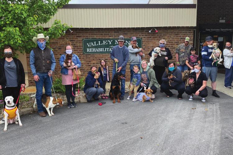 FAMILY AND FRIENDS gather outside Valley Manor Nursing &amp; Rehabilitation Center with their pets after parading around the outside of the facility to visit quarantined residents.