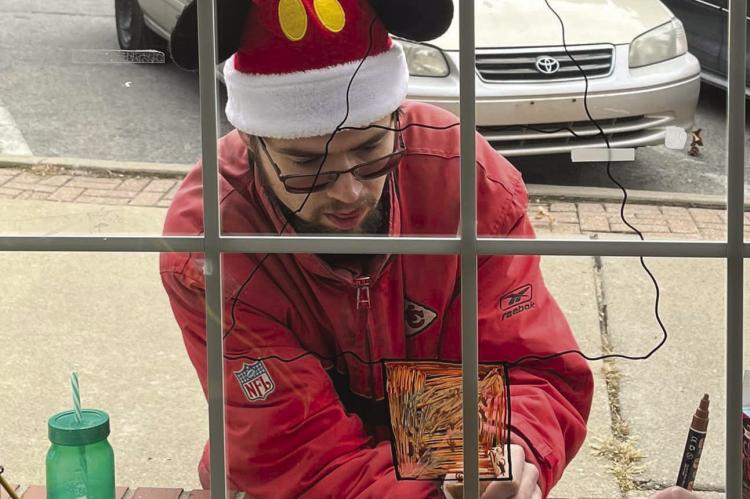 Robbie Farabee sketches Christmas art on the Richmond News window with window art markers. SOPHIA BALES | Staff