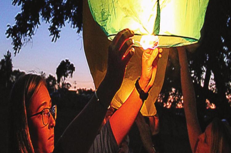 SHYLO MANROE lifts a lantern in honor of Trint Phillips at Century Park.