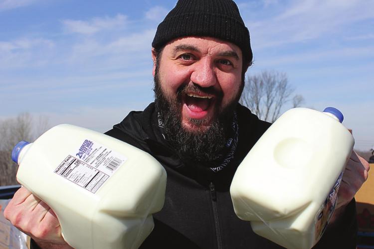JUGS OF MILK held by Pastor Brandon Block are included among the items in the food for distribution.