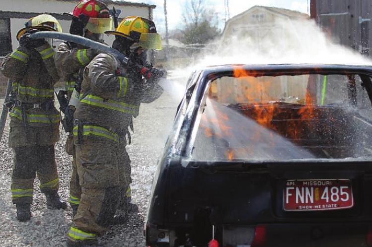 A FIREFIGHTING TEAM – Alloura Stevens, Orrick; Steven Ruby, Excelsior Springs; and Noah Armstrong, Liberty – direct the stream from the firehose and multiple-use nozzle into the hot spots of a burning car. J.C. VENTIMIGLIA | Staff