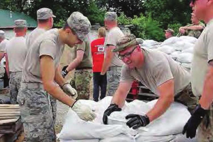 AFTER SANDBAGGING in Hardin, Reserve Staff Sgt. Matt Carroll pushes a sandbag into place in Henrietta. The Guard has been activated now to fight COVID-19.