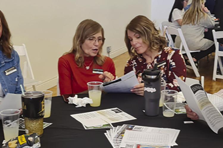 MICHELLE GOODE (from left), April Belcher, Kandi Harrison, Melissa Bartlett and Bill Hightower look over a community survey at the Excelsior Springs Chamber meeting. MIRANDA JAMISON | Staff