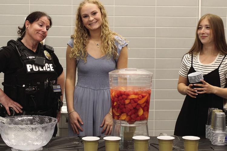 EXCELSIOR SPRINGS Police Department Officer Kristina Baxter (from left) guards the punch bowl while Excelsior Springs High School Student Council member Lundyn Smith and President Reese O’Dell serve the guests.