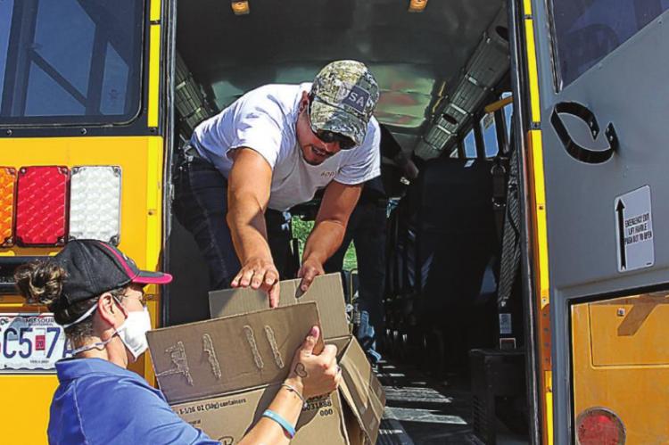 WORKING TOGETHER to load food onto a bus, Rachel Brown hands a box to Josh Echaue.