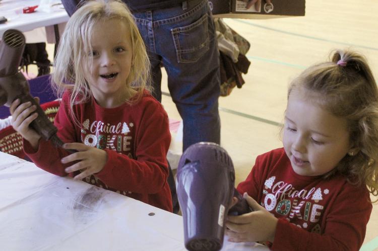 LILLY (LEFT) AND Emmy Remboldt blow-dry their handprint creations at the Elf Factory event hosted at the Community Center. MIRANDA JAMISON | Staff