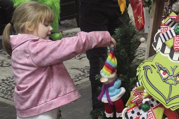 AURORA TAFF looks at Christmas tree decorations while waiting to see the Grinch at Wild Bunch.