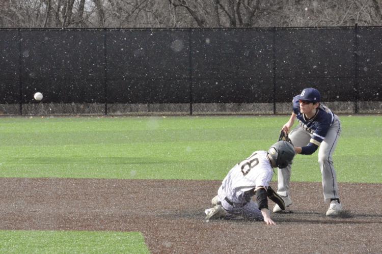 AS SNOW flurries fall and the baseball sails through the air, Excelsior Springs senior Lucas Dillman gets down as he slides into second. SHAWN RONEY | Staff